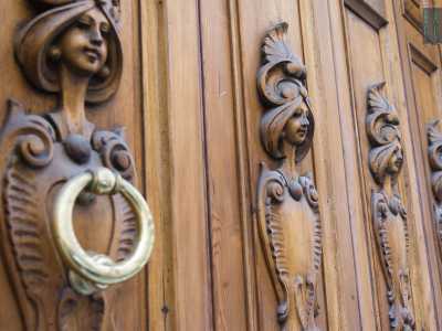 Foto 8. Racchiuso in una doppia cornice in cemento chiaro con arco a tutto sesto e una chiave di volta a testa di leone, il portone liberty presente in ognuna delle quattro ante una figura femminile stilizzata (Foto di Gennaro Gargiulo)